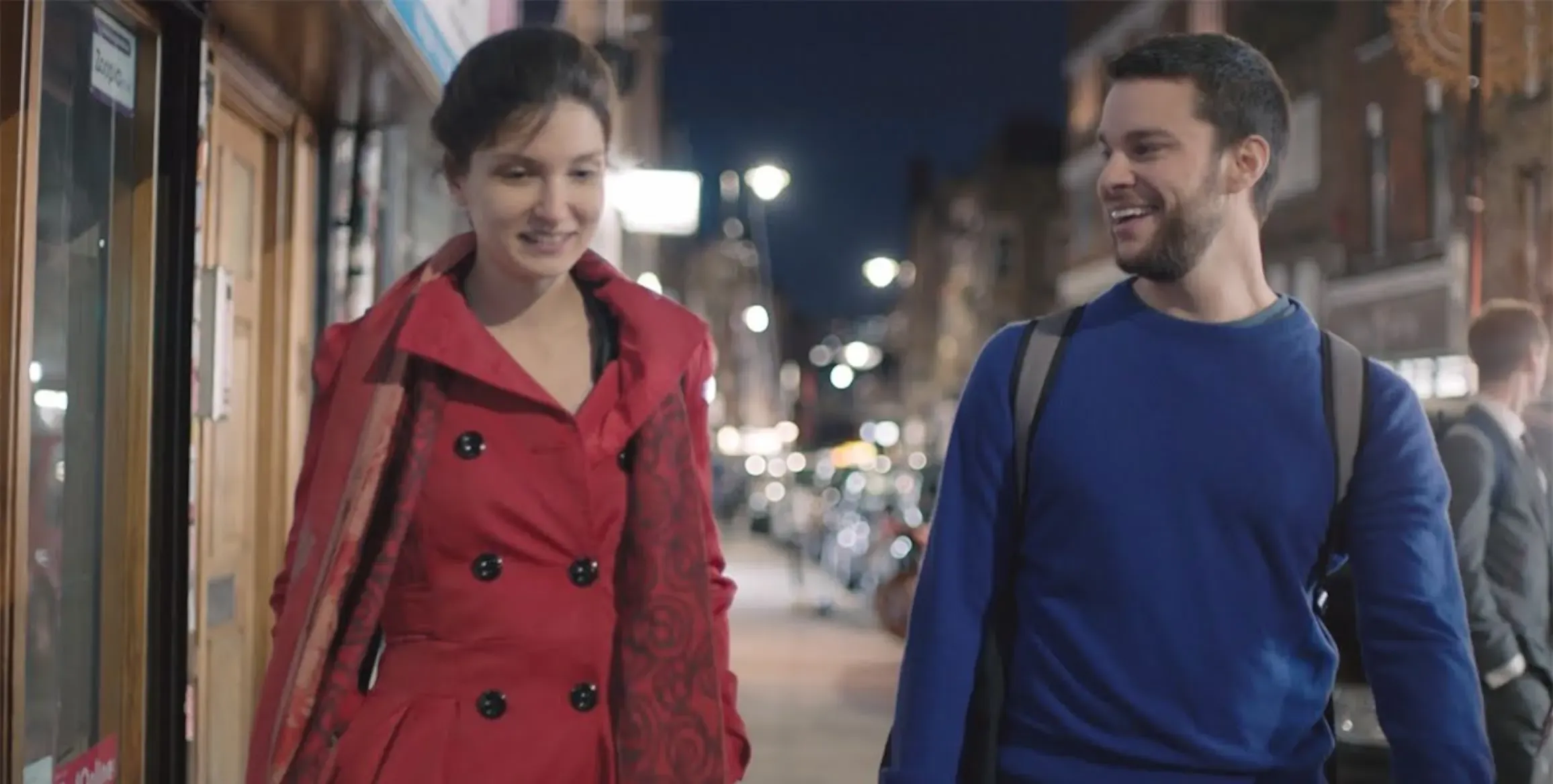 Founders, Elina and Adam, are walking along a sidewalk at night.