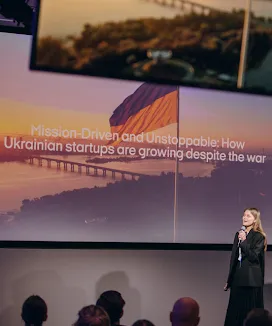 A woman in conference listening to speaker.