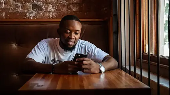 Man sitting in cafe looking at his phone