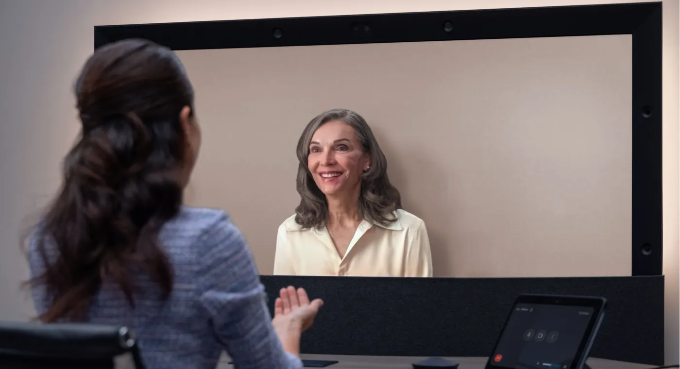 A carousel of images and videos shows the evolution of Google Beam devices over time.
Two people converse and gesture during a Google Beam video meeting.