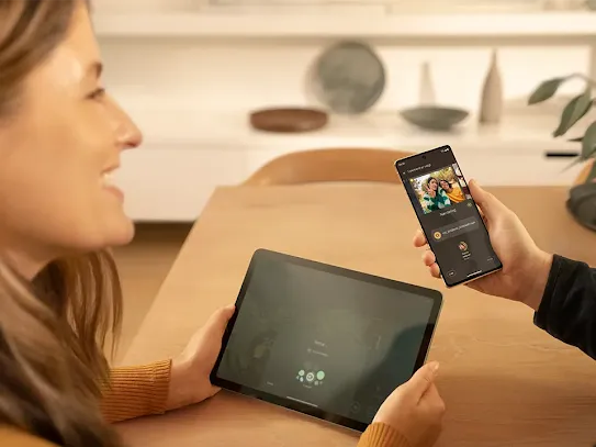 Man and woman using their devices, he uses a smartphone and the woman uses a tablet.