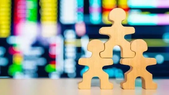 three wooden block figurines in front of a multicolored screen