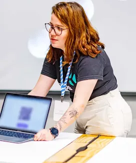 Uma mulher mostrando algo em um laptop.