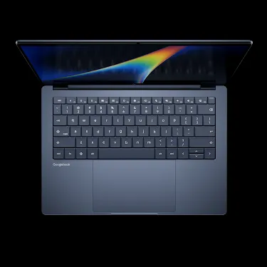 Googlebook laptop open, viewed from above, showing the keyboard and rainbow-gradient display.