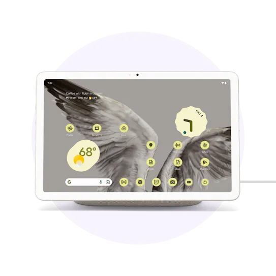 A white tablet on a charging dock with a cord. Its screen shows an abstract bird image and multiple interface icons.