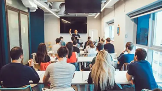 Founders sit at desks in a Google for Startups Campus Tel Aviv classroom, looking up at Google product expert at front of room.