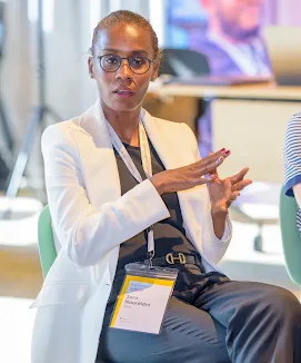 Professional woman in a white blazer speaking at an event.