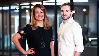 Founders Tatiana and Everton pose in front of an office space