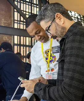 Two people are looking intently at a mobile phone.