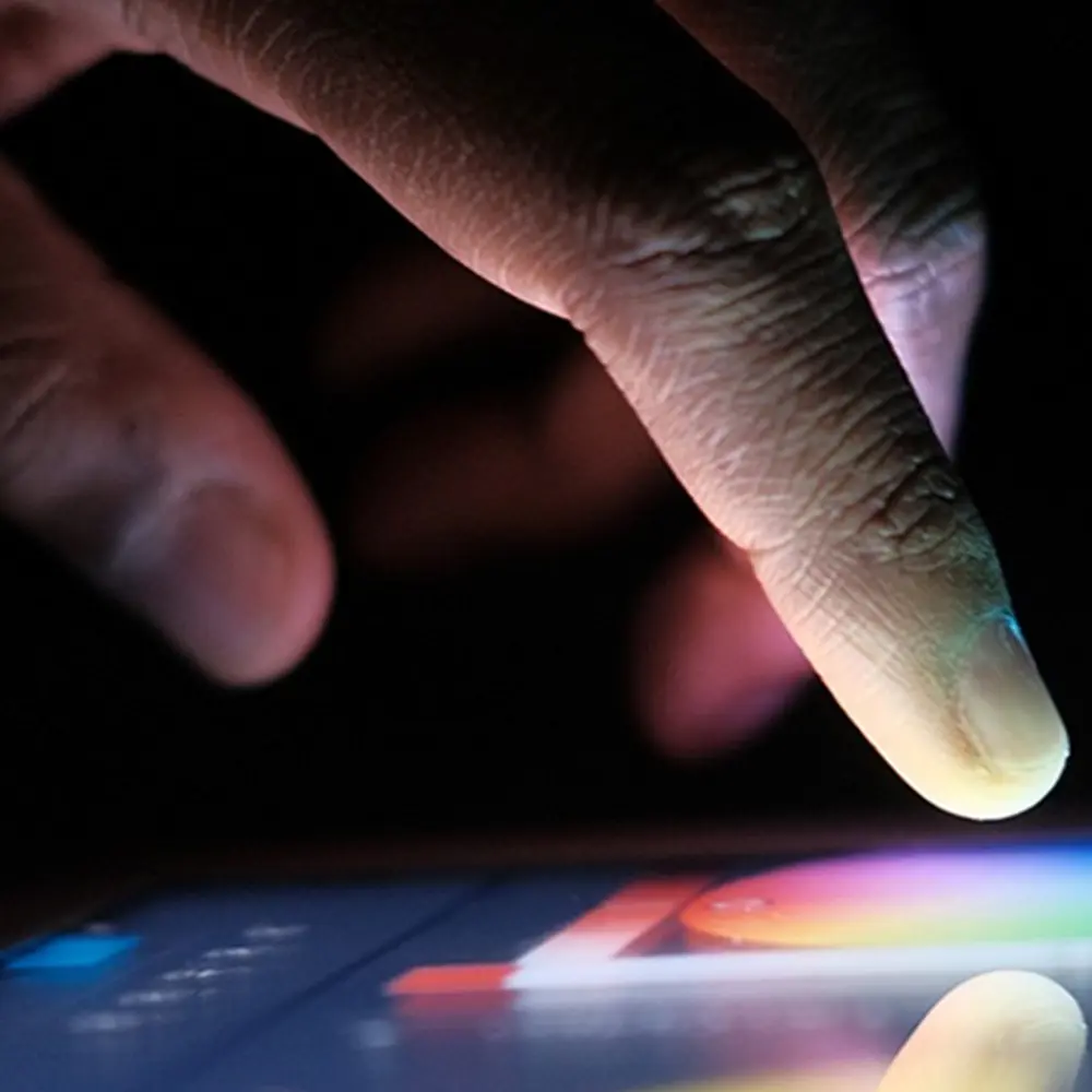 A finger hovering over a phone screen with a rainbow color wheel