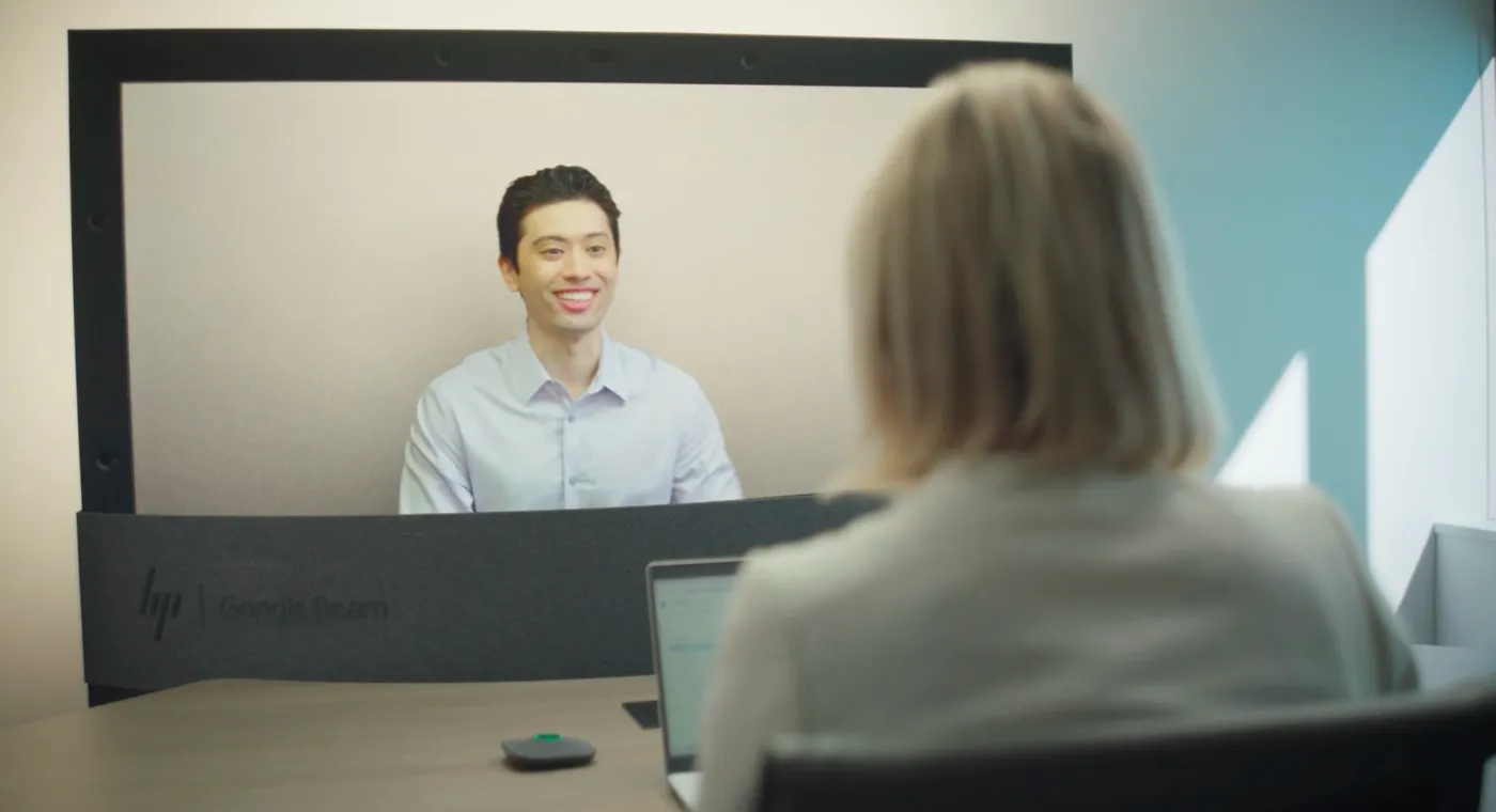 A carousel of images and videos shows the evolution of Google Beam devices over time.
Two people converse during a Google Beam video meeting.