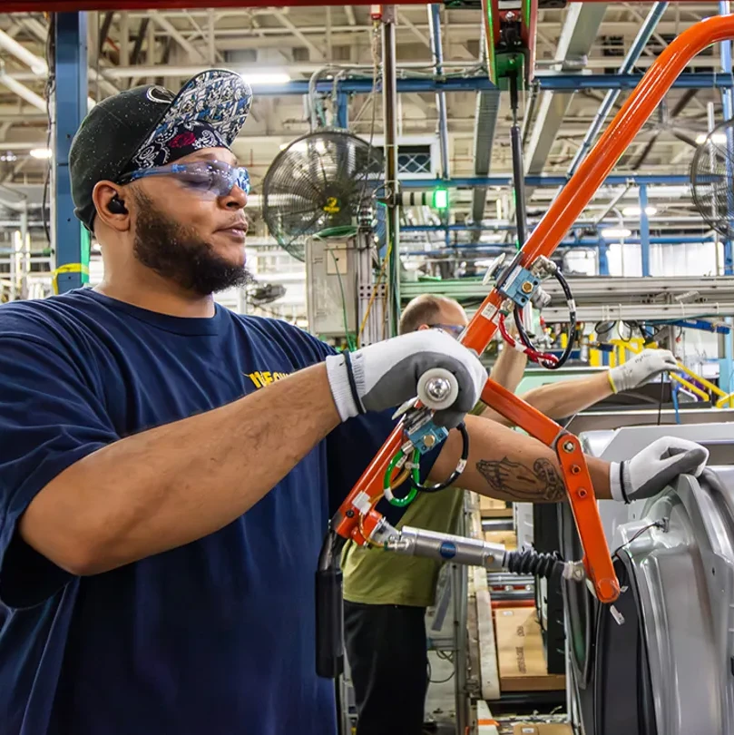 An American automotive works uses a tool to refine a part in a factory.