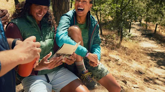 Some hikers laugh while talking and looking at a map.