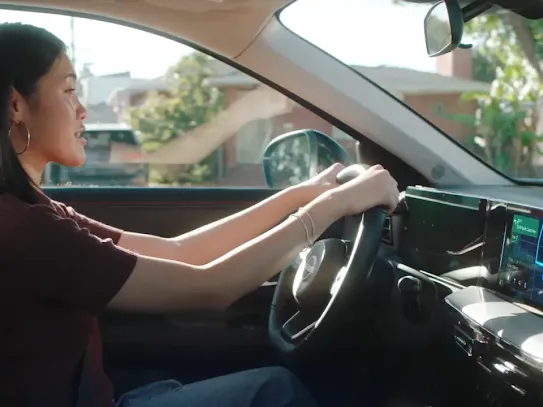 Woman driving a car with an electronic device on the dashboard, featuring a GPS map.