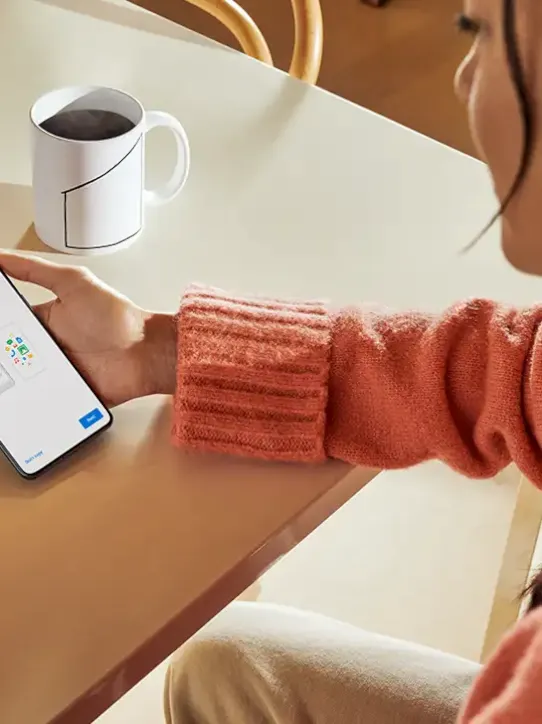 Mulher usando um smartphone, que exibe uma tela de configurações do aparelho.