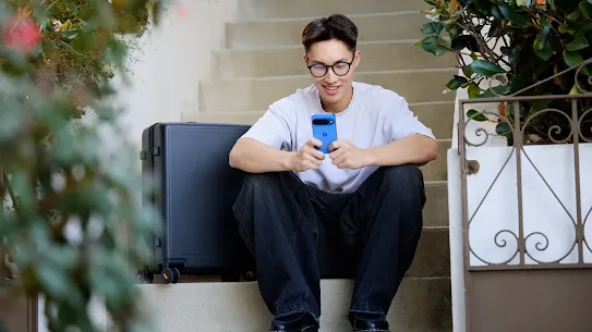 Man using his Android smartphone while sitting on the stairs outside of a building.