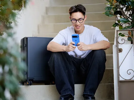 Man using his Android smartphone while sitting on the stairs outside of a building.