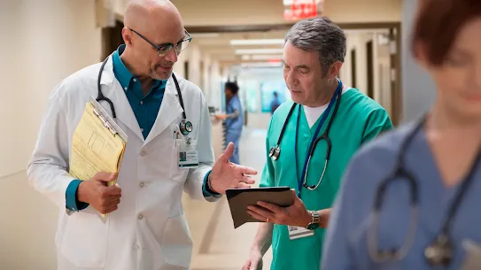 Two male doctors walk down the hall in conversation 