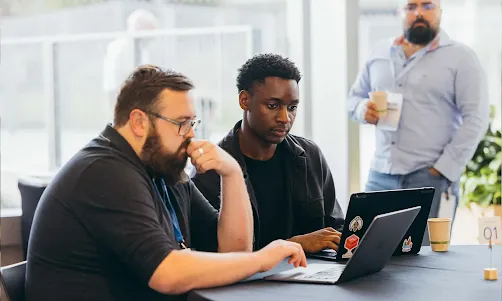 Dos fundadores colaborando en un proyecto y mirando la pantalla de un portátil
