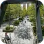 A tree-lined pedestrian path in a city viewed from an elevated position, with dappled sunlight on the pavement.