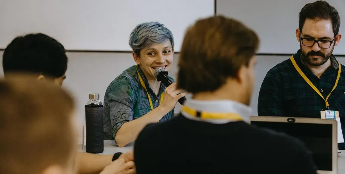 Tina Bychkova, Head of Digital Marketing, is speaking at a conference with colleagues.