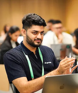 Person wearing an ID card speaking near an open laptop.
