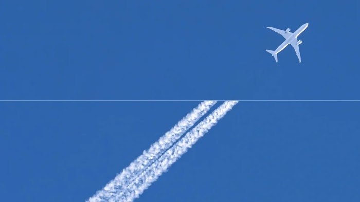 Un avion sur fond de ciel bleu laissant derrière lui des traînées de condensation