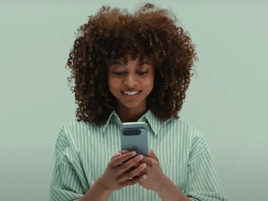 Mulher utilizando o smartphone com atenção e sorrindo.