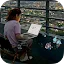 A woman sitting outdoors at night using a laptop with 3D geometric icons and data points floating around the screen.