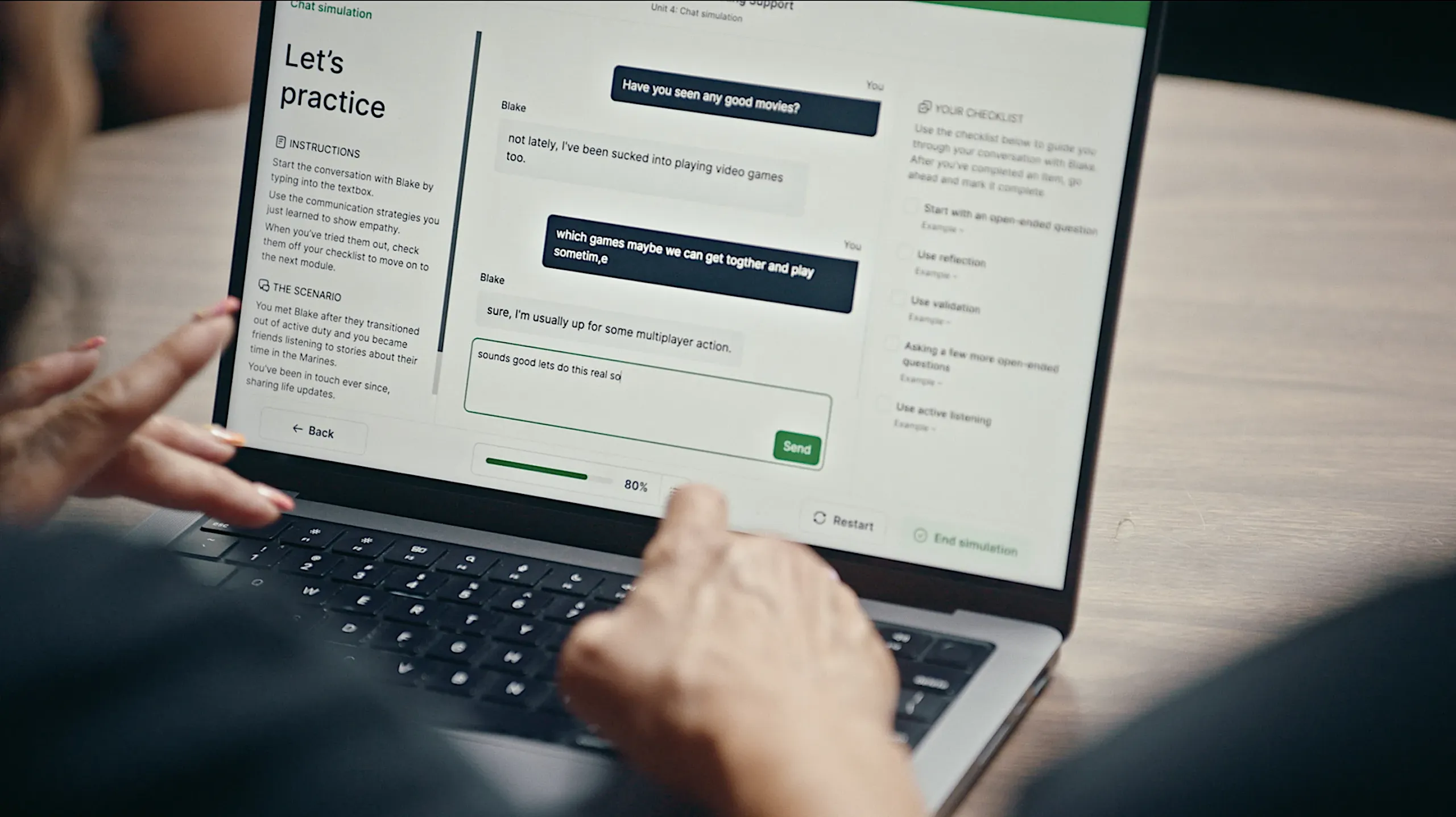 A close-up of a laptop screen showing the HomeTeam "Let’s practice" chat simulation. The interface features a dialogue with an AI persona named Blake, a scenario description about a fellow Marine, and a checklist of communication strategies like "Use validation" and "Active listening."