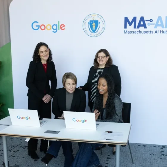 Four people with Google laptops in front of a backdrop displaying Google, Massachusetts, and MA-AI logos.