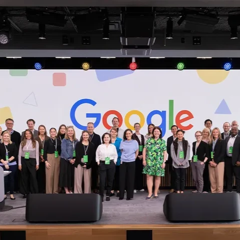 A group of people standing in front of a Google sign at the New York office