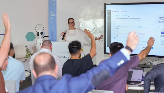 In a happy setting, the host is presenting, and attendees are raising their hands, ready to answer.