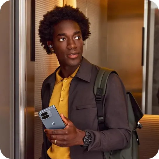 A young man holding a smartphone and wearing a backpack, standing in an elevator.