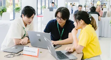 Three people seated around a laptop, collaborating and looking at the screen.