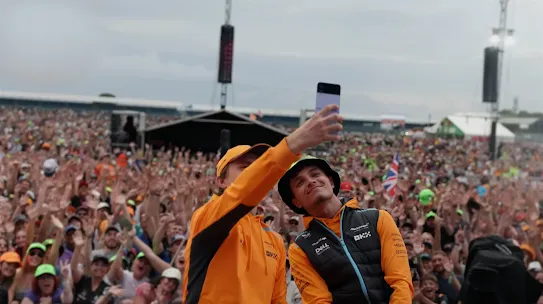 Mclaren ambassidors taking a selfie with a large fan base in the background with an Android device