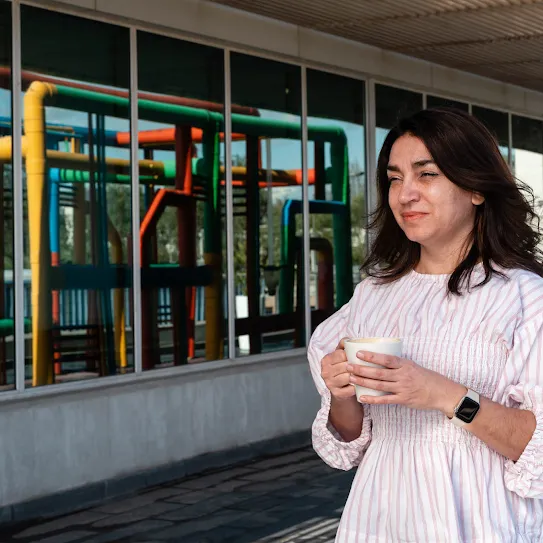 Googler Pia Quiroz carries her coffee across the Quilicura Chile data center campus with the data center pipes reflected in the window behind her