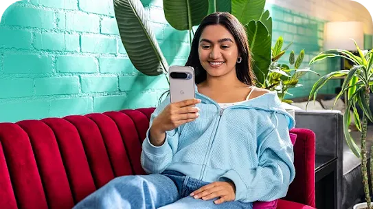 Woman sitting on bed with Android phone
