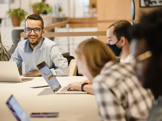 Photograph of Media Tradecraft team members laughing at a desk with laptops out.