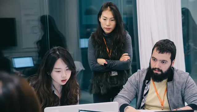 3 men and a woman sitting around a table, discussing.