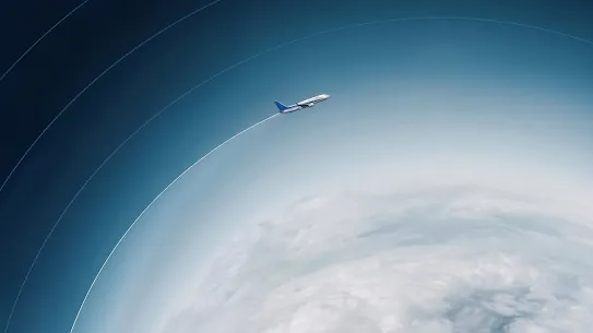 A high-altitude view of a commercial airplane flying above a layer of clouds, with a distinct white contrail trailing behind it.