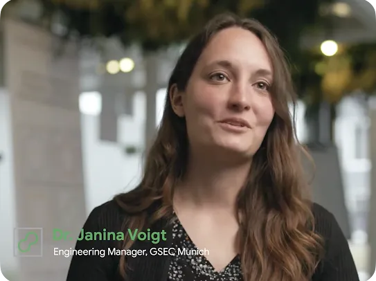 A video interview still of Dr. Janina Voigt, Engineering Manager at GSEC Munich, speaking in a bright, modern office setting with a green plant logo in the corner.