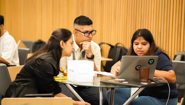 Three team members collaborating and reviewing data on a laptop screen.