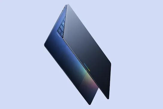 A sleek Googlebook laptop angled against a light blue background, showcasing its thin design, unique triangular keys, and a light bar on the touchpad.
