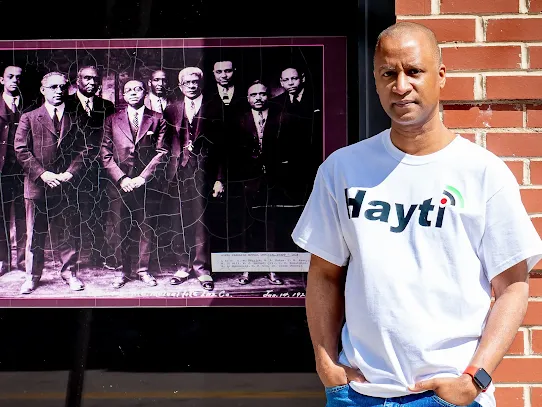 Cary poses next to a vintage portrait of Black leaders, representing a modern digital Black Wall Street