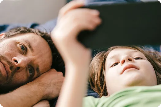Two people, a man and a child, looking at a mobile device.
