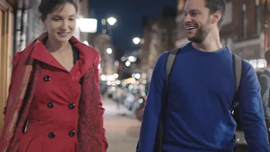 Founders, Elina and Adam, are walking along a sidewalk at night.