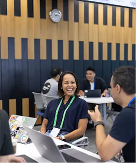 Men and women having a discussion at an event table with a laptop.