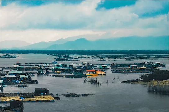 Landscape image of a town that is currently flooded, showing houses from far away that have rising water surrounding them