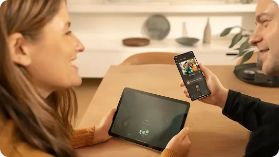 Man and woman using their devices, he uses a smartphone and the woman uses a tablet. 